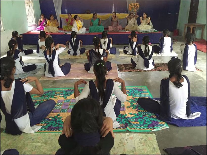 Students sitting on mats in a hall