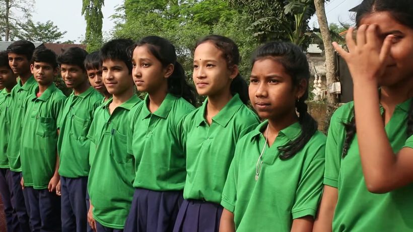 Students in green uniforms standing in a line outdoors