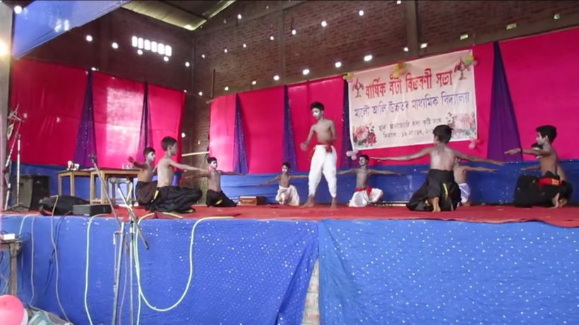 Boys performing a dance on stage under a banner for the annual prize-giving