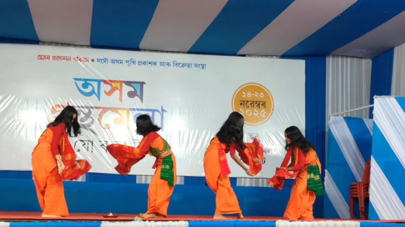 Four students in orange costumes dancing on stage