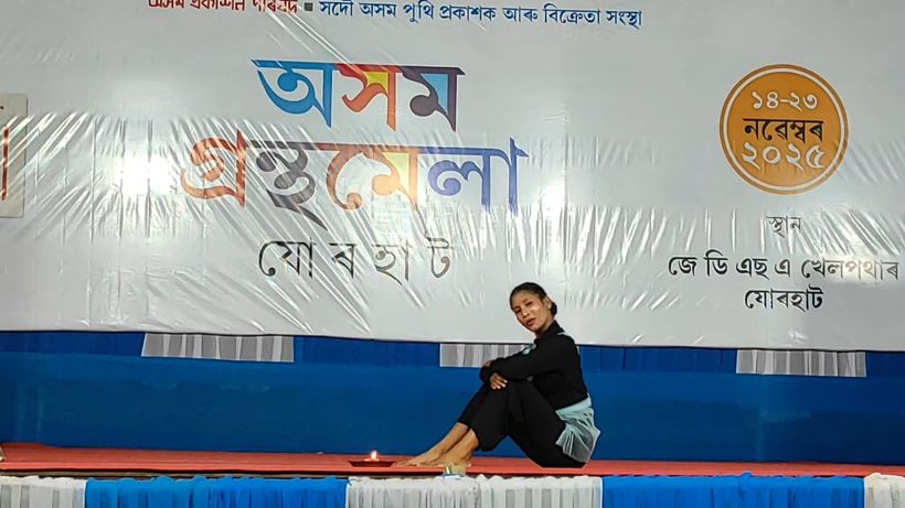 A dancer seated on the stage floor in black