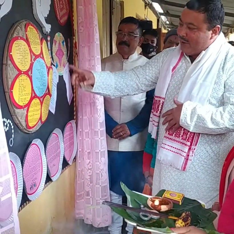 A guest in a gamosa pointing at a painted wall display