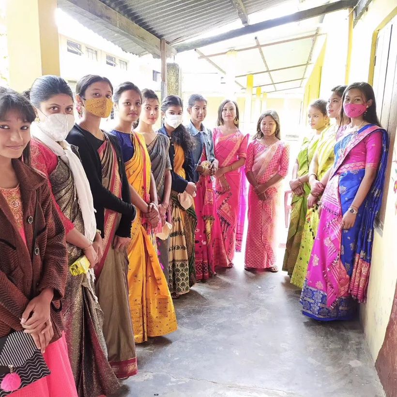 Teachers and students in mekhela chador lined along a school corridor